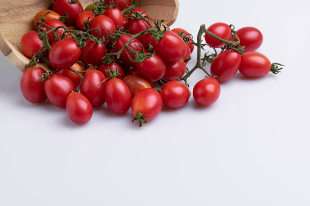Pile of red grape tomatoes in wooden bowl, isolated on white background - Valokuva, kuva