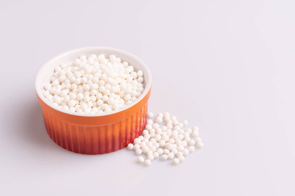 Perles de tapioca ou graines de sagu dans un ramequin orange, isolées sur fond blanc
 - Photo, image