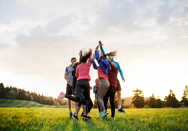 Large group of fit and active people jumping after doing exercise in nature. - Zdjęcie, obraz