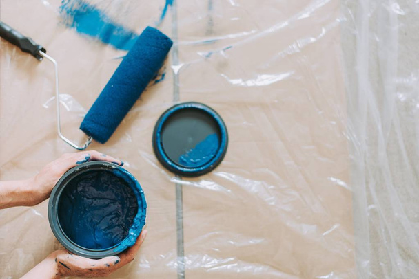 Primo piano di una persona che utilizza rulli di vernice con il colore blu
 - Foto, immagini