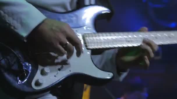 The guitarist playing on the electronic guitar on the concert. The man with guitar stands on the scene and performs a music. Musician plays guitar at the rock concert. Illumination is blinking around the rock-guitarist. - Filmmaterial, Video