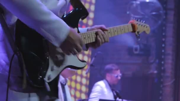 The guitarist playing on the electronic guitar on the concert. The man with guitar stands on the scene and performs a music. Musician plays guitar at the rock concert. Illumination is blinking around the rock-guitarist. - Filmmaterial, Video