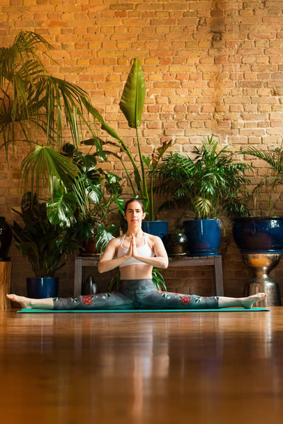 jalá Mujer joven practicando yoga en estudio. Sentado en la alfombra verde
. - Foto, imagen