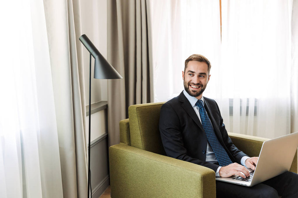 Attractive young businessman wearing suit sitting in a chair - Fotografie, Obrázek