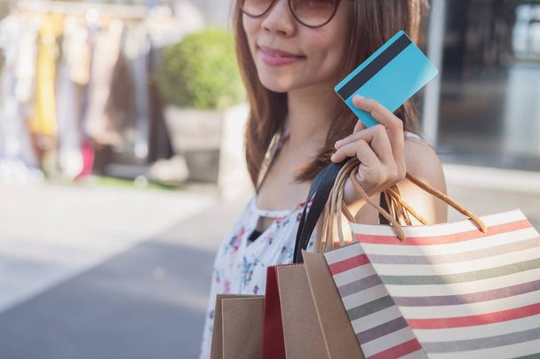 Young woman with shopping bags and credit card at shopping mall  - Foto, Imagen
