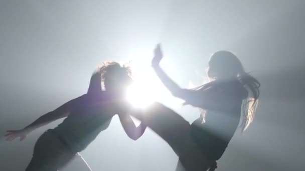 Fêmeas musculares praticando capoeira em raios de holofotes no estúdio. Close-up câmera lenta
 - Filmagem, Vídeo