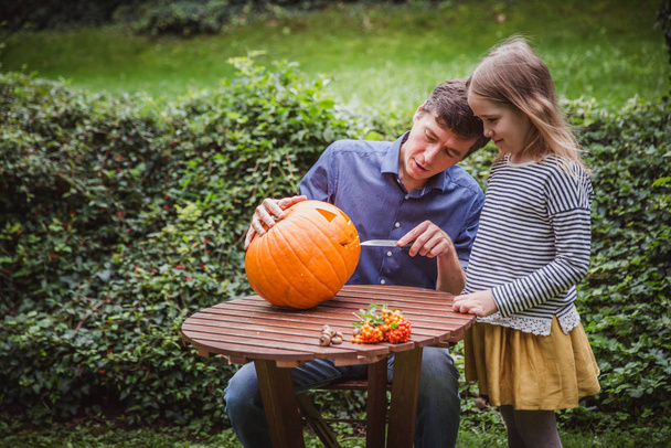 Joyeux Halloween. Père et fille sculptant citrouille pour Halloween à l'extérieur
. - Photo, image