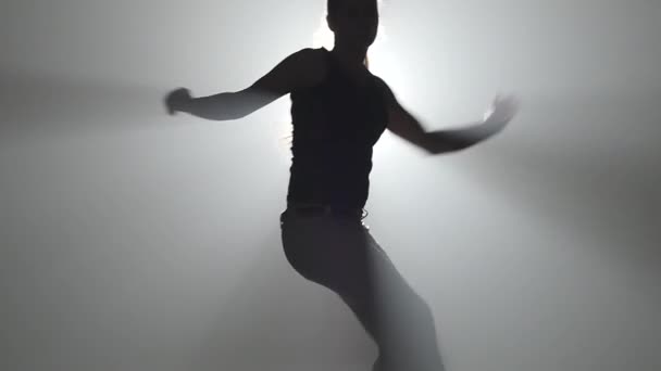 Close-up slow motion. Young girl practicing capoeira in ray of spotlight in studio. - Felvétel, videó
