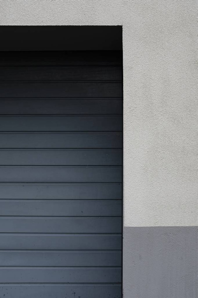Lato di una porta garage in metallo su una parete bianca e grigia
 - Foto, immagini
