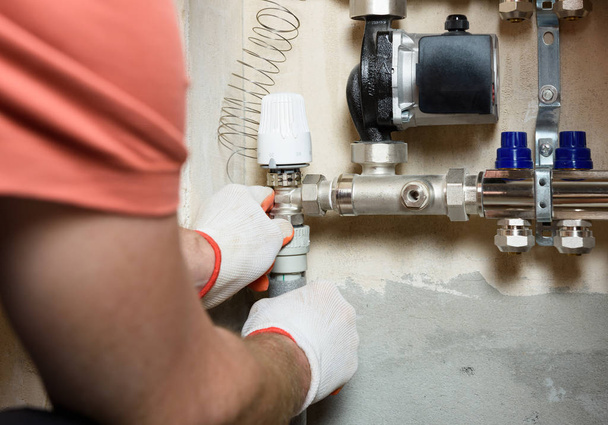 A worker is connecting the pipes to a home heating system distributor. - Photo, Image
