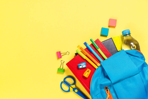 School backpack with stationery on yellow background. - Photo, image