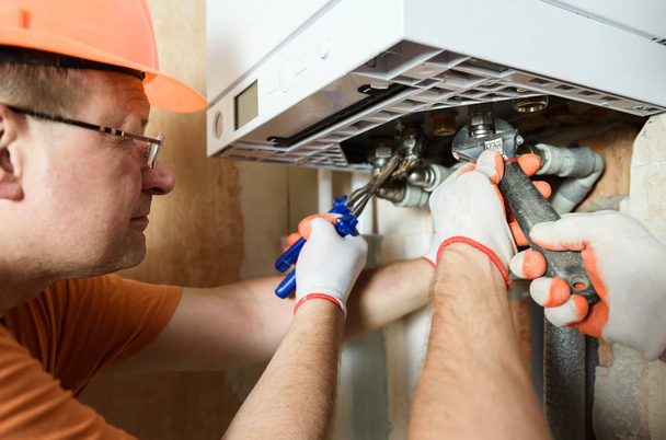 Pracownik instaluje przewody kotłów gazowych. - Zdjęcie, obraz