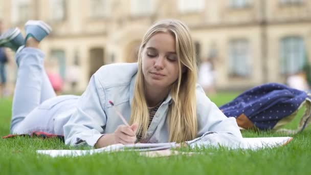 Tired student girl lying on the grass in the park. - Video, Çekim