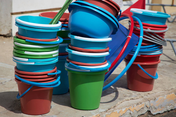 Muitos baldes de plástico multicoloridos vazios ficam perto da entrada do edifício
 - Foto, Imagem
