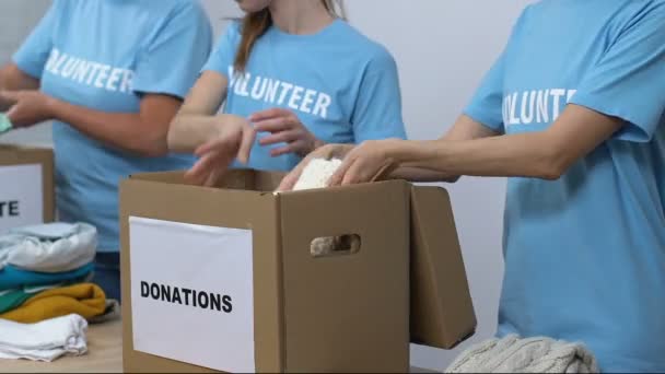 Group of volunteers packing clothing in boxes, friendly lady smiling to camera - Materiaali, video