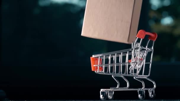 Shopping cart with carton box falls down, delivery related super slow motion shot - Πλάνα, βίντεο