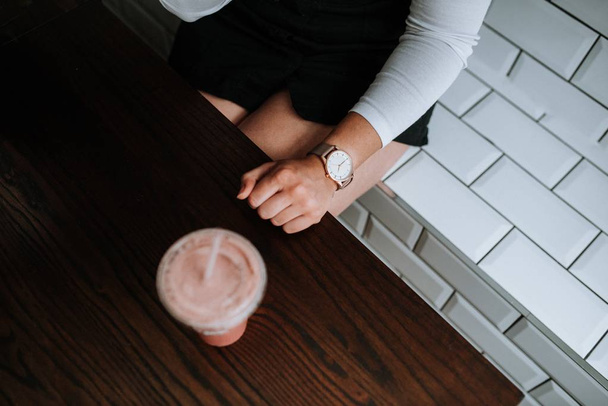 Female sitting on a white decorative brick bench with a strawberry milkshake next to her - Foto, immagini