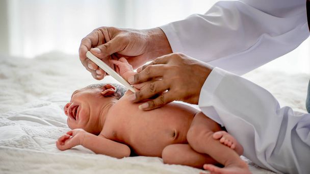 Мягкое размытие изображения рук врача использовать термометр измерить температуру новорожденного ребенка в процессе проверки или лечения ребенка
. - Фото, изображение