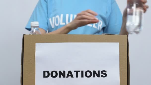 Volunteer packing food in cardboard box, gathering donations for nursing home - Materiaali, video