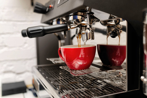 máquina de café preparando café fresco e derramando em copos vermelhos no restaurante
 - Foto, Imagem