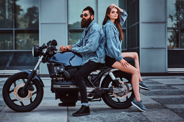 Portrait of couple in denim jackets with motorbike - Фото, изображение