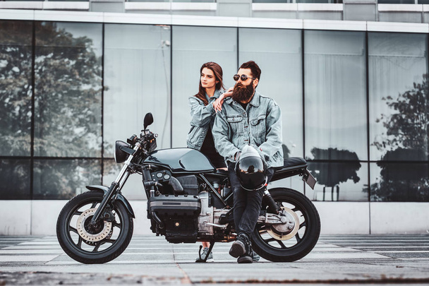 Portrait of couple in denim jackets with motorbike - Zdjęcie, obraz