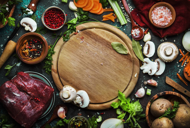 Food cooking background. Fresh organic vegetables, ingredients, spices and meat for warm autumn soup on vintage kitchen table with rustic wooden cutting board. Top view, place for text. Domestic cooking and eating concept - Foto, Imagem