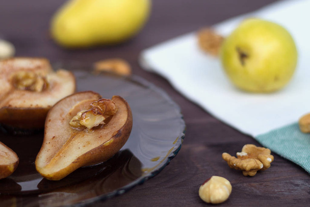 baked pears on dark glass plate with fresh fruits and nuts wooden background - 写真・画像