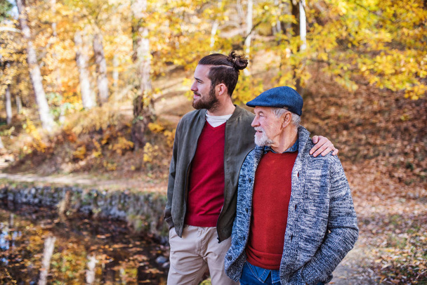 Старший отец и его сын гуляют на природе, разговаривают
. - Фото, изображение