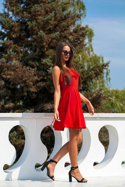 Young beautiful woman in red dress on the summer street - Fotó, kép