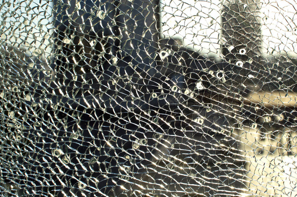 gebroken glas tegen de achtergrond van de stad, kogelgaten - Foto, afbeelding