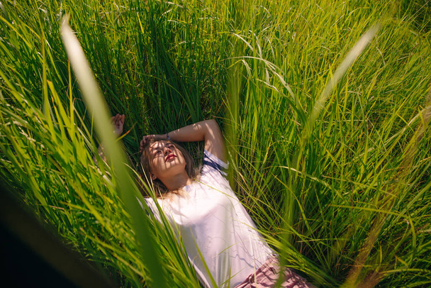 T-shirt design concept - beautiful girl lies in grass in blank white t-shirt - Fotó, kép