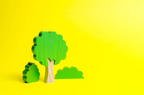 Figures en bois d'arbres et de buissons sur fond jaune. Le concept de forêt et de nature. Préserver l'environnement contre l'influence humaine. Déforestation illégale. Restauration des habitats naturels
 - Photo, image