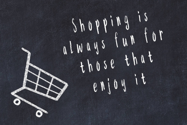 Chalk drawing of shopping cart and short quote about shopping on black board - Zdjęcie, obraz