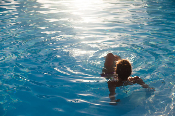 Beautiful young woman swimmimg in luxury pool - Photo, Image