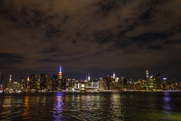 Manhattan 's nachts schot van veraf met rivier reflectie - Foto, afbeelding