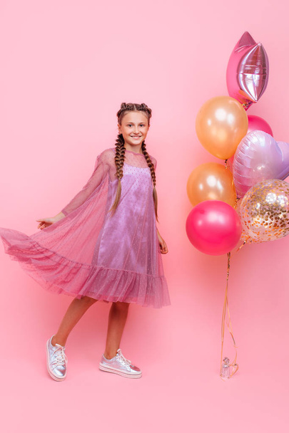 Happy and beautiful teen girl holding a bunch of colorful balloo - Фото, зображення