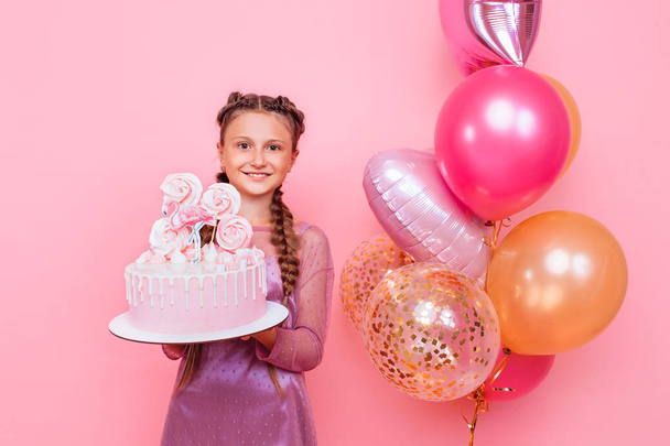 A teenage girl with balloons holds a cake in her hands, on a pin - Foto, immagini