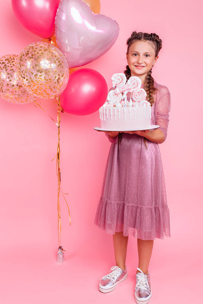 A teenage girl with balloons holds a cake in her hands, on a pin - Photo, Image