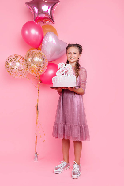 A teenage girl with balloons holds a cake in her hands, on a pin - Photo, Image