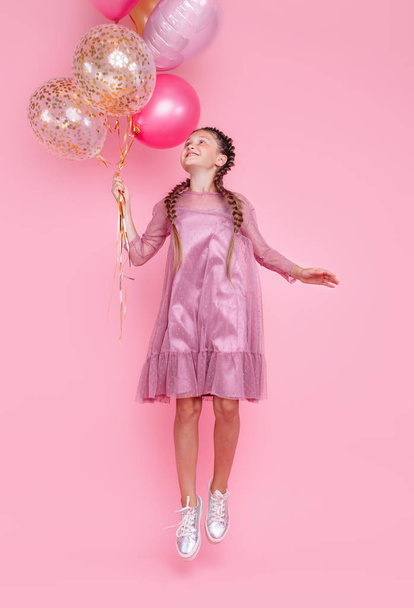 Happy teenage girl jumping high with balloons isolated on pink b - Valokuva, kuva