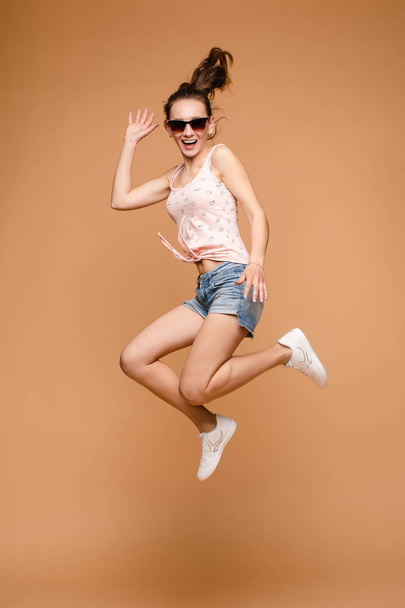 陽気ブルネット若いです女性でカジュアル見通しジャンプで空中でスタジオ. - 写真・画像