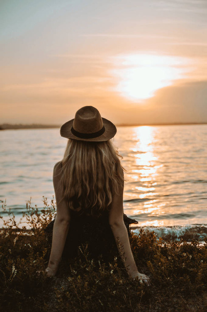 Stylová žena v čepici s kloboukem na pláži při západu slunce. - Fotografie, Obrázek
