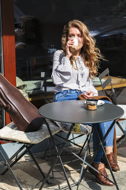 Κορίτσι βιολιστής κάθεται στο διάλειμμα καφέ στο καφέ - Φωτογραφία, εικόνα