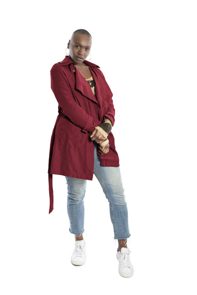 Black African American fashion model with bald hairstyle confidently posing with a red colored jacket for fall collection.  Depicts fashion design and clothing apparel - Photo, Image