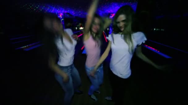 drei Mädchen tanzen und blasen dann Küsse in Nahaufnahme im Hintergrund von Bowlingbahnen - Filmmaterial, Video