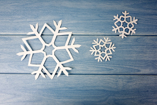 origami paper snowflakes on blue wooden table surface, winter concept - 写真・画像