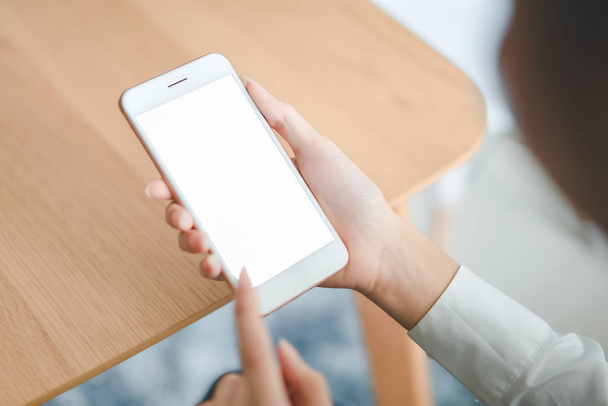 Mulher mão segurando smartphone com tela em branco na mesa no café. Pegue sua tela para colocar em publicidade
. - Foto, Imagem