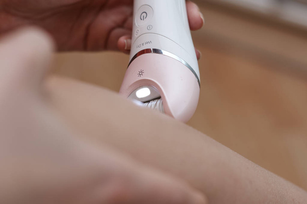 youngg woman with epilator removing hair  - Foto, Bild