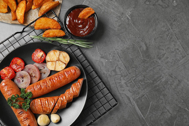 Delicious grilled sausages and vegetables on grey table, flat lay. Space for text - 写真・画像